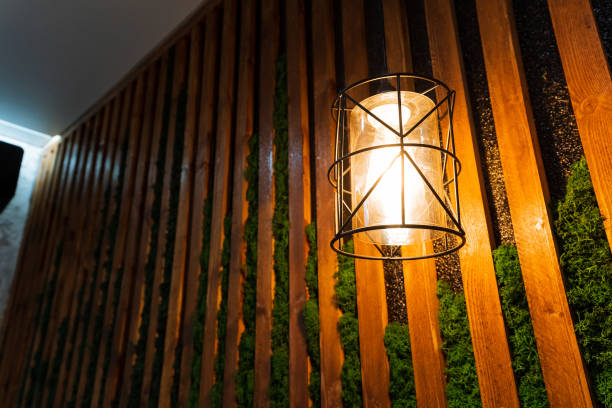 A beautiful lamp is elegantly hanging on a rustic wooden wall, which is adorned with soft green moss that is thriving on its surface, adding a touch of nature to the decor