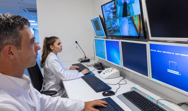 istock Male and female MRI technicians monitor patients on monitors. MRI technical room control table. COVID-19 2204662461