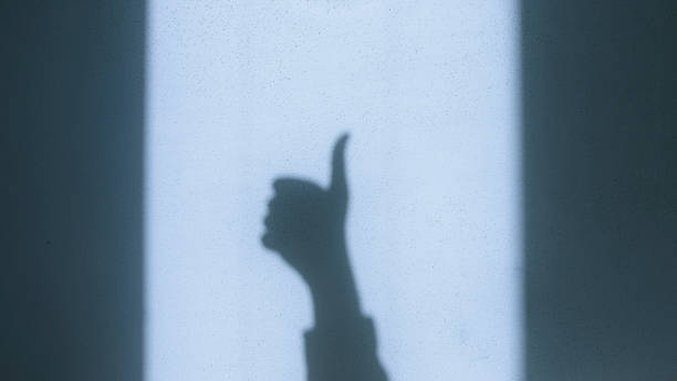 Shadow of a Hand Showing a Thumbs-Up Gesture on a Sunlit Wall
