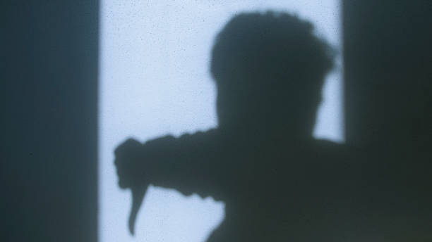 istock Shadow of a man making a thumbs-down gesture against a sunlit wall, symbolizing disapproval, rejection, or dissatisfaction with strong contrast and minimalist composition 2204662602