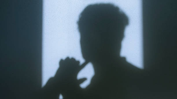 Shadow of a man with hand gesture symbolizing distress and depression against a sunlit wall, evoking deep emotions, struggle, and inner turmoil