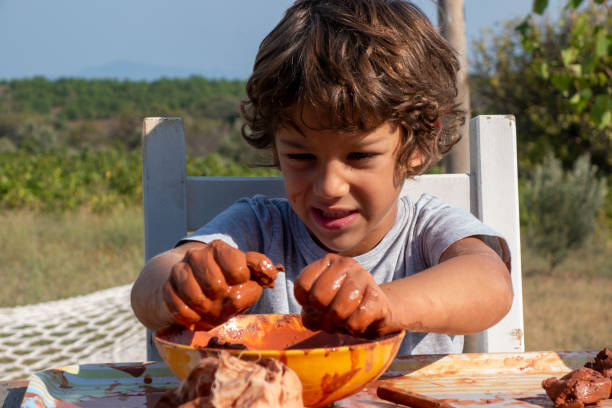 istock Boy playing with ceramic clay. He works for his creativity. A 9-year-old boy playing with ceramic clay in a bowl. He works at the table on the porch of the house. 2204664661