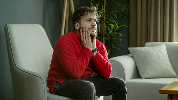 istock Young Man Sitting Thoughtfully in a Cozy Living Room, Lost in Deep Thoughts 2204664962