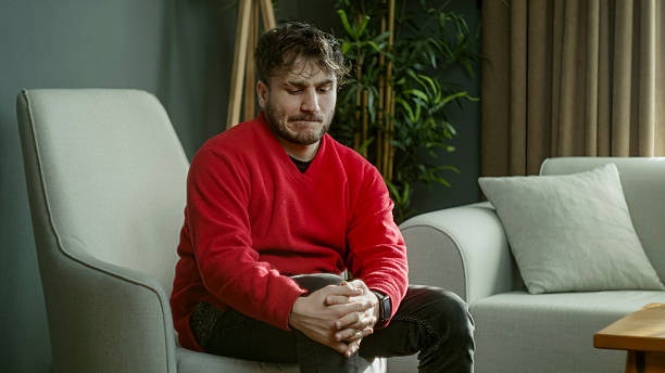istock Young Man Sitting Thoughtfully in a Cozy Living Room, Lost in Deep Thoughts 2204666138
