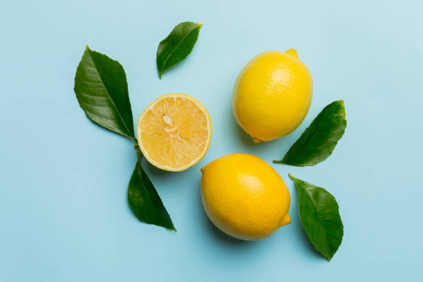 istock Many fresh ripe lemons with green leaves on colored background, top view, space for text 2204666673