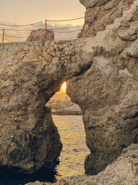 istock A rock formation with a hole in it and a sun shining through it in a cala in mallorca 2204671525