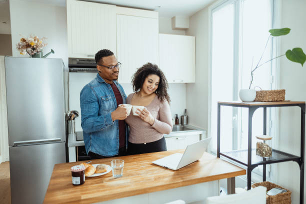 istock Multiracial married couple at home drinking coffee and using laptop at kitchen counter 2204672275