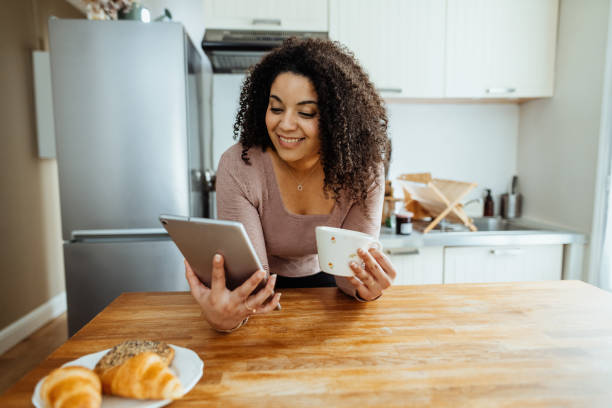 istock Single woman working at home on kitchen counter, using digital tablet while enjoying coffee 2204672387