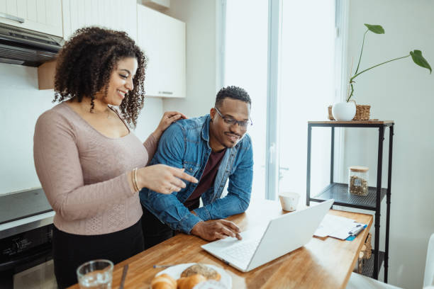 istock Multiracial married couple at home drinking coffee and using laptop at kitchen counter 2204672721