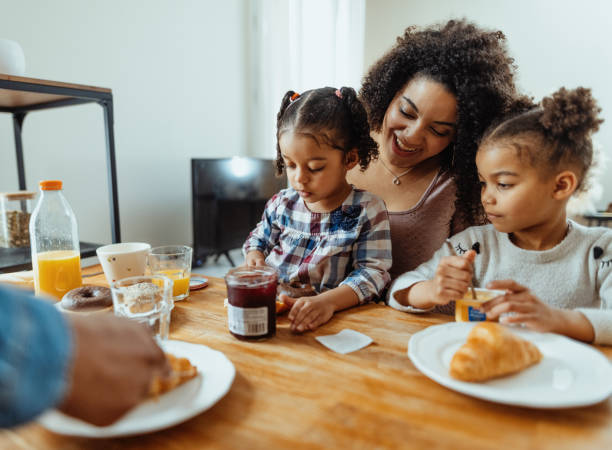 Family with two little daughters enjoying breakfast together