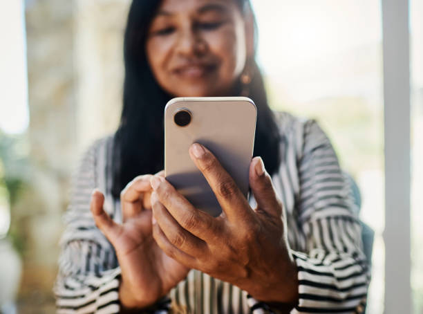 istock Smiling Woman Holding Smartphone in Bright Setting 2204673715
