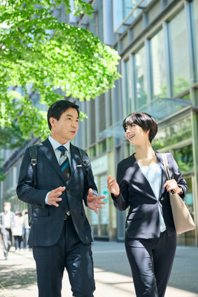 A 50-something male office worker and a 30-something female office worker walking through a business district