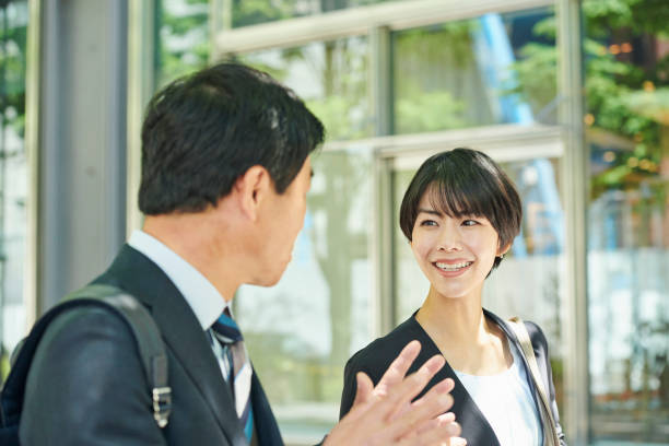 istock A 50-something male office worker and a 30-something female office worker walking through a business district 2204674753