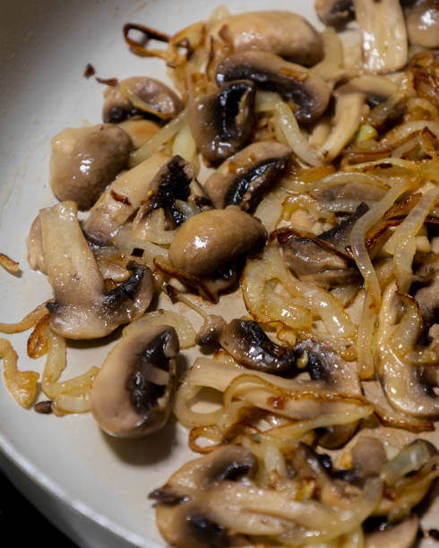 istock cooking mushrooms and onions in a white pan close-up 2204675352