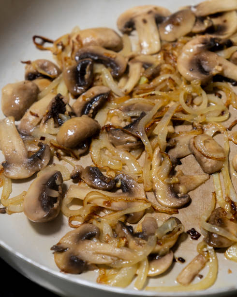 istock cooking mushrooms and onions in a white pan close-up 2204675361