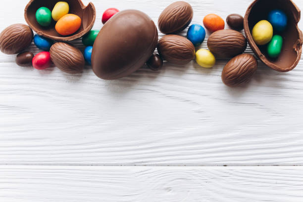 istock Chocolate Easter eggs and rabbit ears on white wooden background. 2204675487