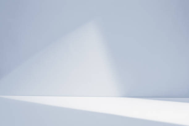 istock Bright sunlight beams illuminating a minimalistic white room background with soft shadows in the early morning 2204675522