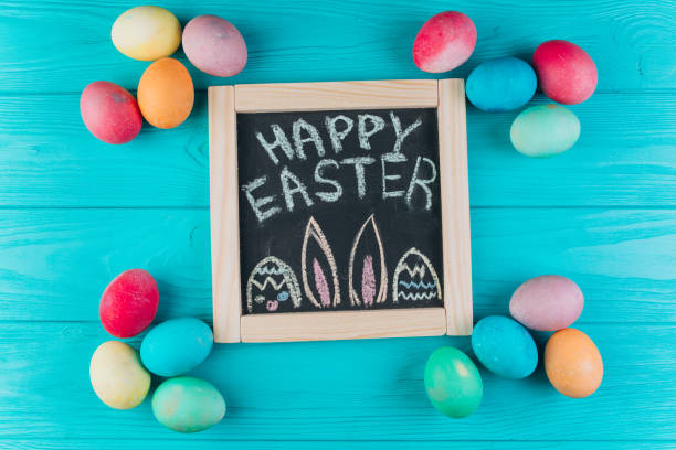 istock Blackboard with the text to Easter around eggs on a blue wooden background. Top view and flat lay. 2204676271