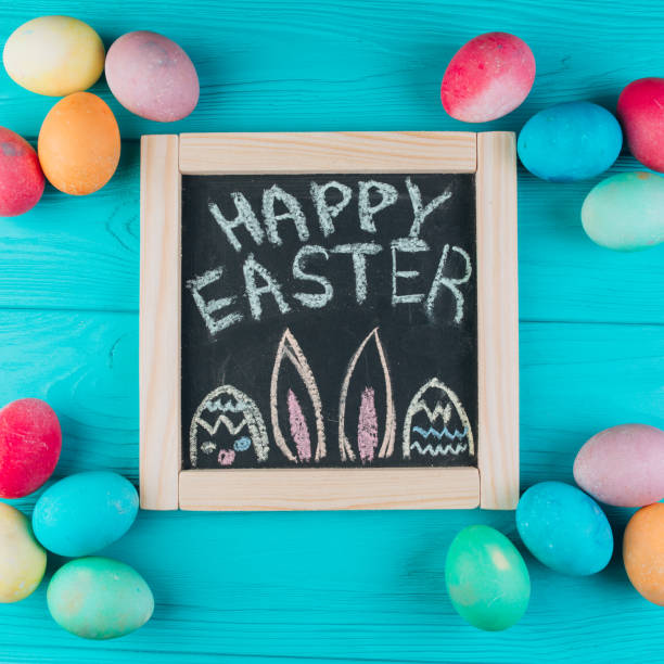 istock Blackboard with the text to Easter around eggs on a blue wooden background. Top view and flat lay. 2204676273