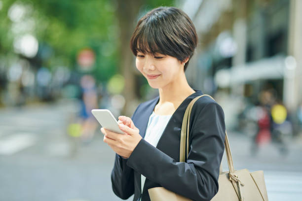 istock A smiling 30-something female office worker checking her smartphone on the street 2204676701