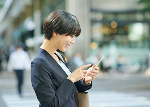 istock A smiling 30-something female office worker checking her smartphone on the street 2204676740
