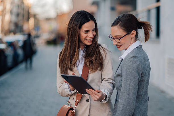 istock Two businesswomen using digital tablet on city street 2204678444