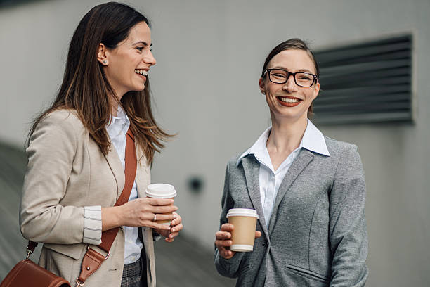 istock Two businesswomen smiling and chatting during coffee break outside office 2204678476