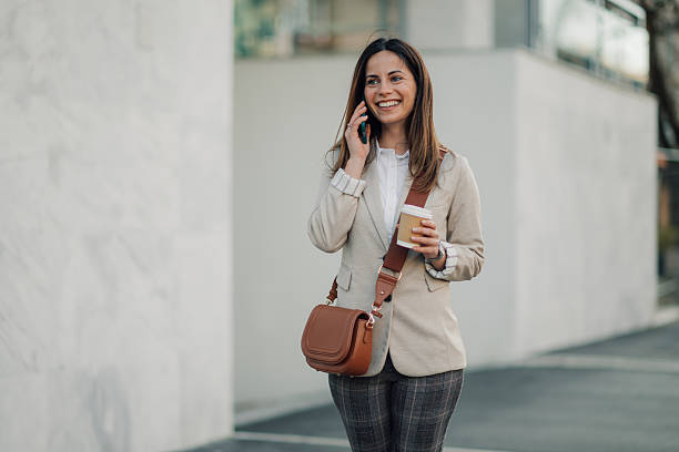 istock Businesswoman walking and talking on the phone while holding a coffee 2204678489