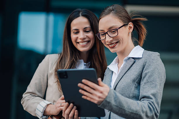 istock Two businesswomen smiling and using digital tablet outside office 2204678493