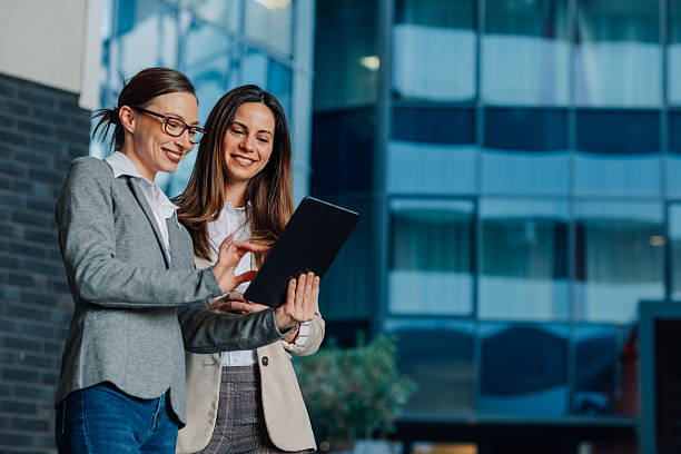 istock Businesswomen using digital tablet outside office building 2204678502