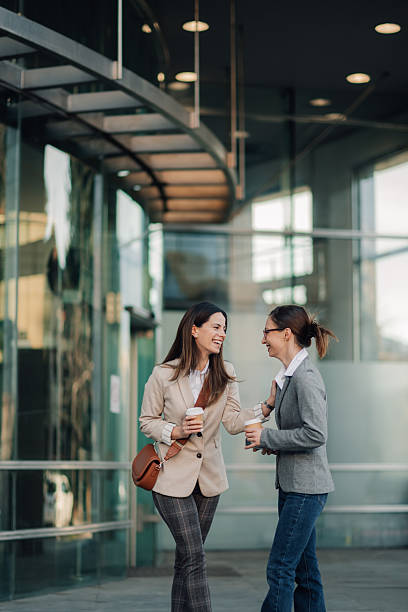 istock Two businesswomen talking and smiling during coffee break outside office 2204678561