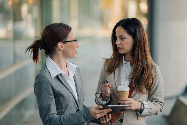 istock Businesswomen talking and holding a digital tablet in a modern office building 2204678564