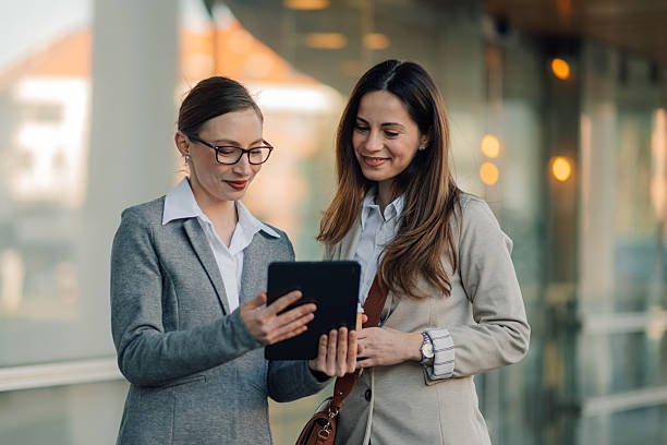 istock Businesswomen using digital tablet outside office building 2204678570