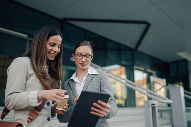 istock Businesswomen using digital tablet and drinking coffee outdoors 2204678575