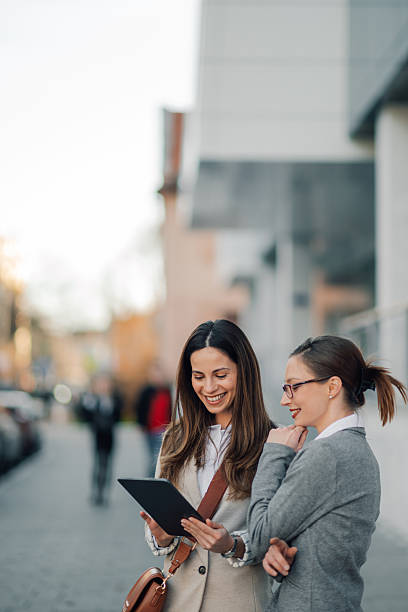 istock Two businesswomen using digital tablet on city street 2204678587