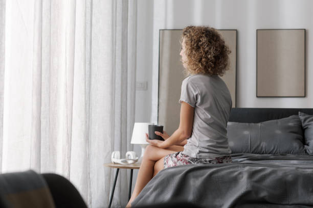 istock Serene woman sitting on bed and drinking coffee 2204678604