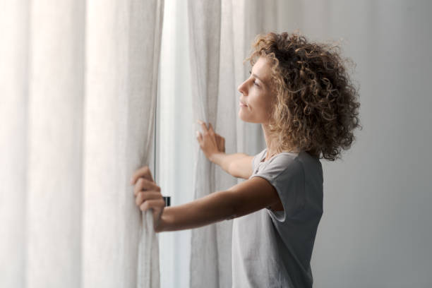 istock Serene woman waking up and looking out the window 2204678781