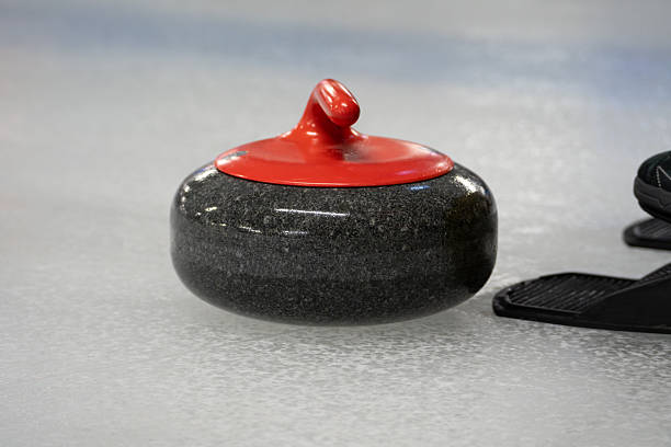 istock Curling stone on the ice rink sheet. Polished and shaped granite rocks with a handle on top, used to play the game of curling. 2204680445