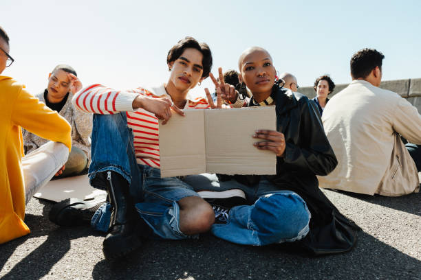 istock Two protestors holding a blank sign while sitting amidst a crowd outdoors 2204681059