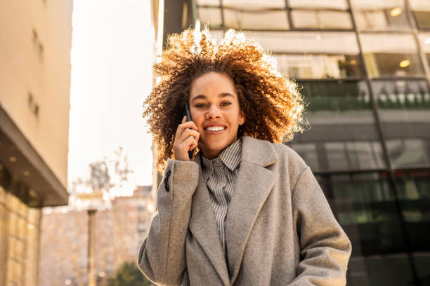 istock Carefree Curly-Haired Woman Smiling While on a Call 2204682180