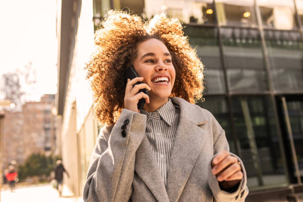 istock Curly-Haired Woman Having a Fun Call on Her Smartphone 2204682242