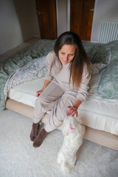 istock Woman sitting on bed with dog 2204684440
