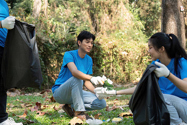 istock Collaboration for a cleaner environment. Volunteers exchanging waste during a park cleanup. 2204684445