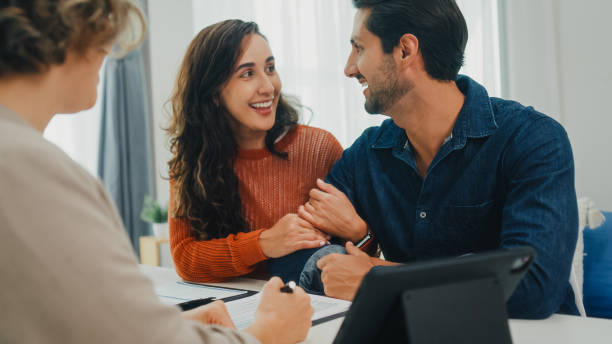istock Financial advisor using digital tablet discussing about life insurance and domestic finances with young couple in living room at home. Financial planning and lifestyles concept. 2204684467