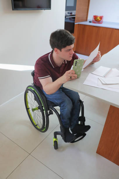 istock Man in wheelchair doing paperwork at home 2204684783