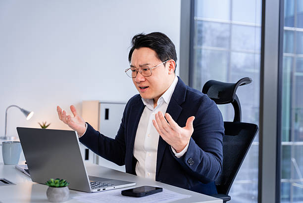 istock Frustrated Businessman Using Laptop in Modern Office Environment 2204687238
