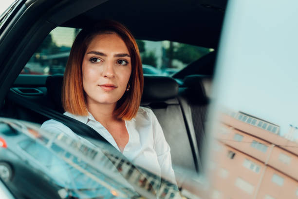 istock Businesswoman sitting in car looking out window while going to work 2204687942