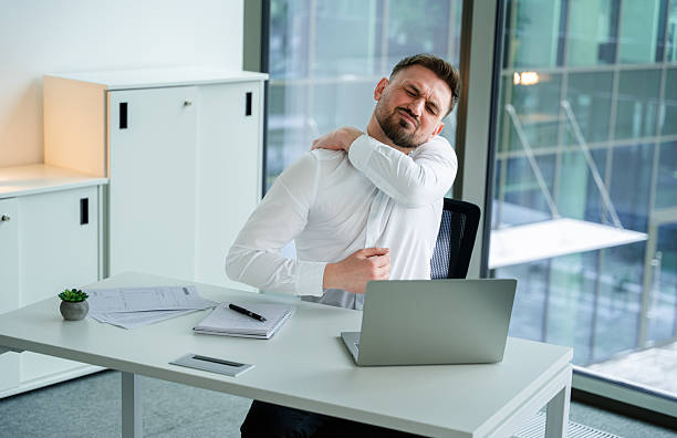istock Businessman Experiencing Shoulder Pain While Working in a Bright Office Setting 2204689113