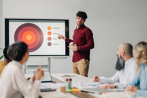 istock Young manager pointing at interactive whiteboard during a presentation to his team in the meeting room 2204690849