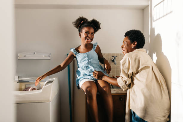 istock Happy mother and daughter doing laundry with a machine at home 2204691136